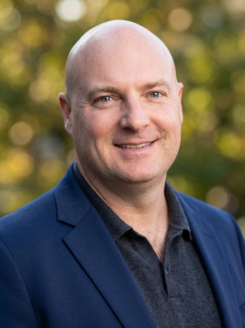 AI headshot of a professional against a soft-focus warm-toned nature blur background